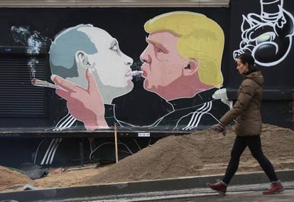 Uma mulher ao lado de um mural com a imagem de Trump e Putin em Vilnius, na Lituânia.