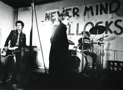Sid Vicious, Johnny Rotten e Paul Cook, membros do Sex Pistols, em um show em 1977. Ao fundo, o título de seu primeiro e único disco, 'Never Mind the Bollocks'.