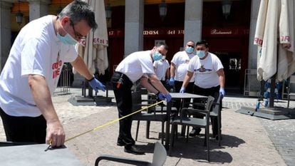 Funcionários montam e fazem a limpeza de mesas de um restaurante no centro de Madri.