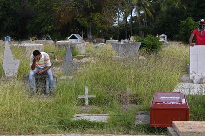 Um homem chora diante de um caixão no cemitério de Güiria, onde foram enterradas as vítimas de um naufrágio no caminho para Trinidad y Tobago.