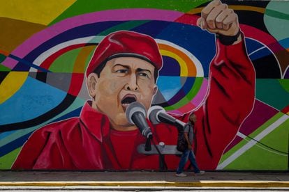 Um homem caminha ao lado de um mural sobre o falecido presidente venezuelano Hugo Chávez, em 8 de novembro de 2021 em Caracas, Venezuela.