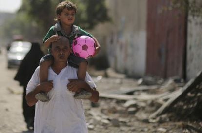Um palestino leva seu filho nos ombros em Gaza.