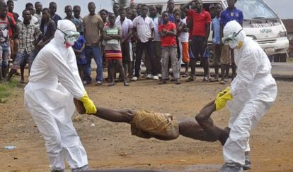 Trabalhadores da saúde retiram cadáver de homem suspeito de morrer de ebola.