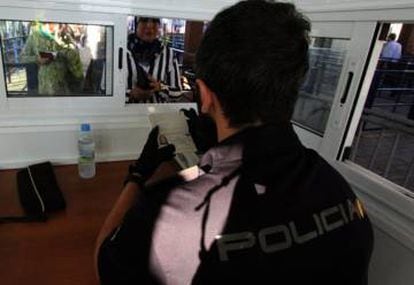 Um agente da polícia nacional verifica a identidade de uma marroquina no posto fronteiriço entre Espanha e Marrocos.