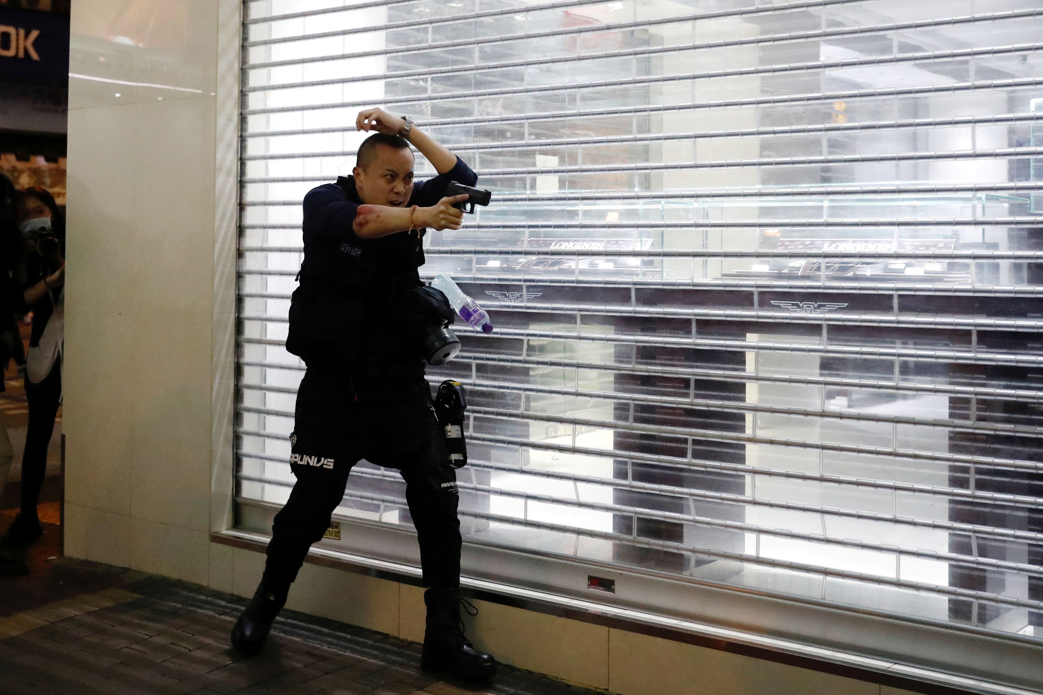 Policial aponta arma para manifestantes em Hong Kong, em fevereiro.