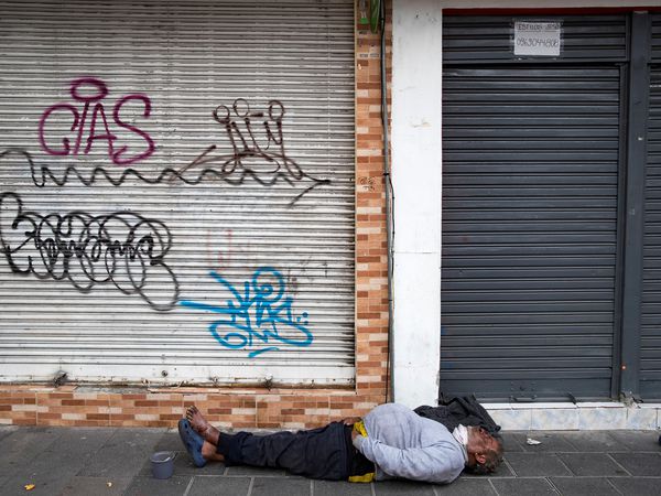 AME5639. QUITO (ECUADOR), 31/07/2020.- Un habitante de calle duerme sin tapabocas mientras militares y policías ecuatorianos patrullan por las calles para contener la aglomeración de personas y detectar las actividades no autorizadas dada la pandemia COVID-19, este viernes en Quito (Ecuador). Las autoridades de Quito continúan sus esfuerzos en el sur de la ciudad para contener la curva de contagios en la capital ecuatoriana, que ya suma 13.342 positivos. EFE/José Jácome