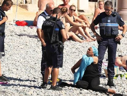 Policiais em Niza obrigam a uma mulher a descobrir na praia.