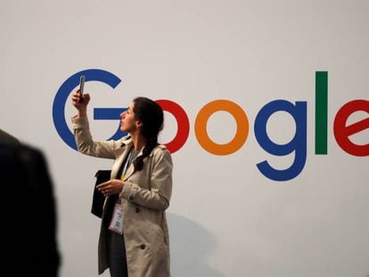 – Usuária consulta seu celular ao lado do logo do Google.