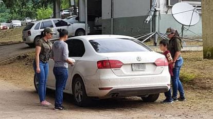 A mulher argentina sequestrada durante 32 anos (com blusão de cor cinza) entra em um carro de polícia com seu filho de 9 anos.
