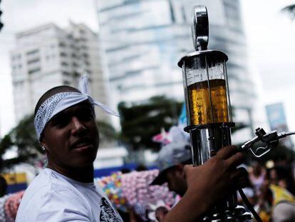 Folião leva cerveja em uma mini bomba de gasolina, sábado em São Paulo.