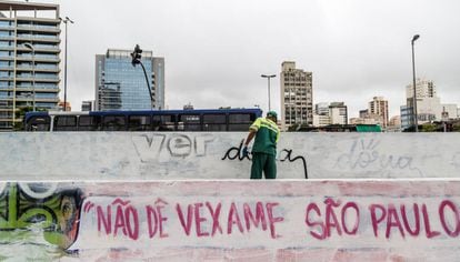 Funcionário apaga pichação contra Doria em São Paulo.