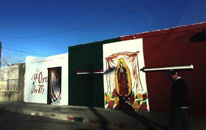 Um mural com imagem da virgem de Guadalupe sobre a bandeira mexicana em Ciudad Juárez.