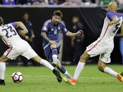 Messi chuta no meio de dois norte-americanos.