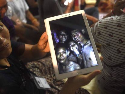 Uma familiar mostra uma foto de alguns dos desaparecidos tirada dentro da gruta pelas equipes de resgate nesta segunda-feira, na Tailândia. 