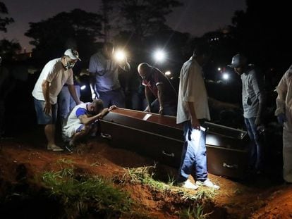 Um homem chora junto ao caixão de seu pai, morto em decorrência do coronavírus, no cemitério da Vila Formosa em São Paulo.