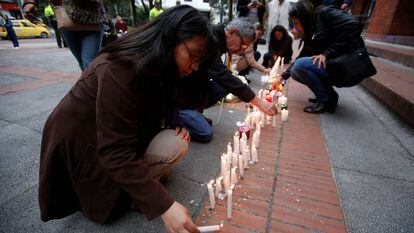 Várias pessoas acendem velas