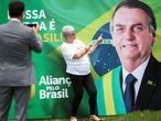 Apoiadora posa em frente a banner que promove o Aliança pelo Brasil. 