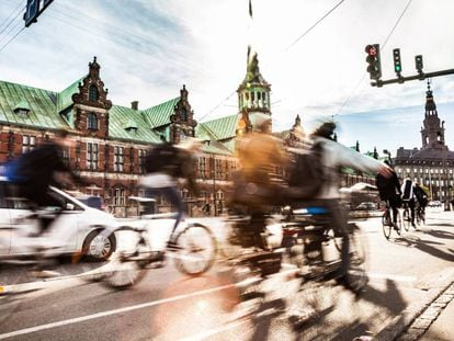 Ciclistas em Copenhague, com o edifício da Bolsa ao fundo