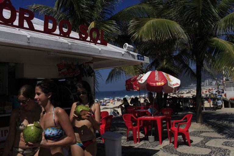 Banhistas tomam coco no calçadão da praia de Ipanema.