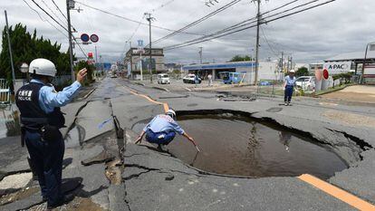 Policial examina cratera aberta pelo terremoto em uma rua de Takatsuki, ao norte de Osaka, na manhã desta segunda-feira