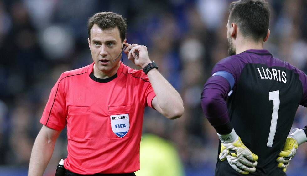 O árbitro da partida entre França e Espanha se comunica com os assistentes.