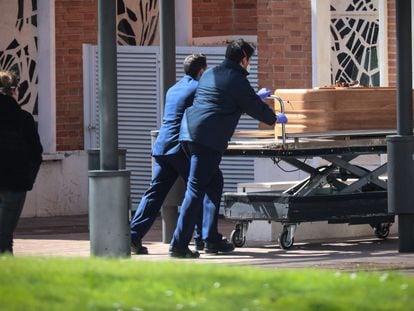 Dois trabalhadores levam um caixão no cemitério de La Almudena, em Madri, em março.