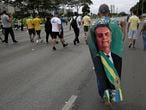 A demonstrator, wearing a cape emblazoned with an image of President Jair Bolsonaro, walks with others to the National Congress, as part of a caravan backing Bolsonaro’s anti-coronavirus-lockdown stance, marking May Day, or International Workers' Day, in Brasilia, Brazil, Saturday, May 1, 2021. (AP Photo/Eraldo Peres)