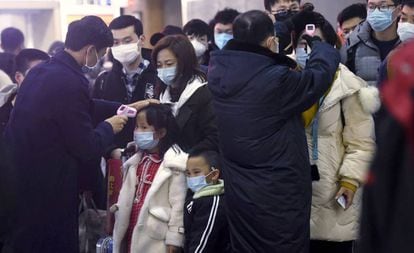 Agentes verificam temperatura de viajantes procedentes de Wuhan na estação de Hangzhou (China).