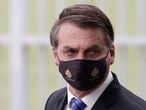 Brazilian President Jair Bolsonaro wears a mask due to the COVID-19 pandemic as he leaves his official residence, Alvorada palace, in Brasilia, Brazil, Monday, May 18, 2020. The logo on the mask reads "Military Police. Federal District." (AP Photo/Eraldo Peres)