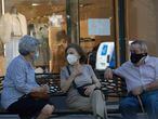 Tres personas con mascarillas conversando en un banco, en Madrid, el pasado miércoles.