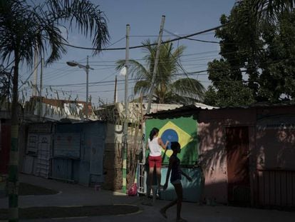 Moradora do Complexo do Alemão, no Rio de Janeiro, pinta a bandeira do Brasil numa parede.