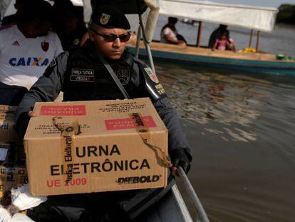 Policial carrega urna eletrônica no Rio Negro, em Manaus.