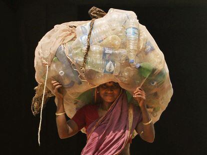 Mulher indiana carrega garaffas pet para vender em um centro de reciclagem, em Bhubaneswar.