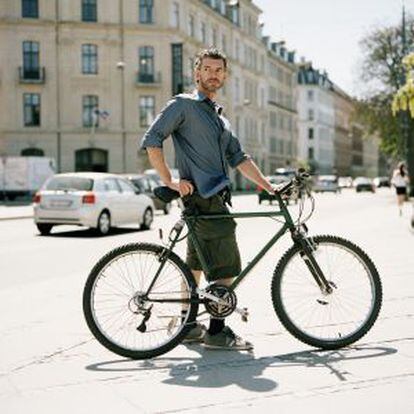 Homem leva sua bicicleta por Copenhague.