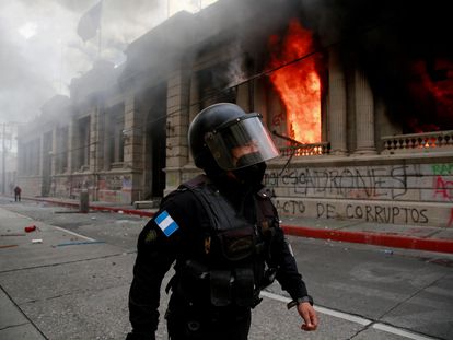 Policial caminha ao lado do Congresso em chamas na Cidade da Guatemala, neste sábado.