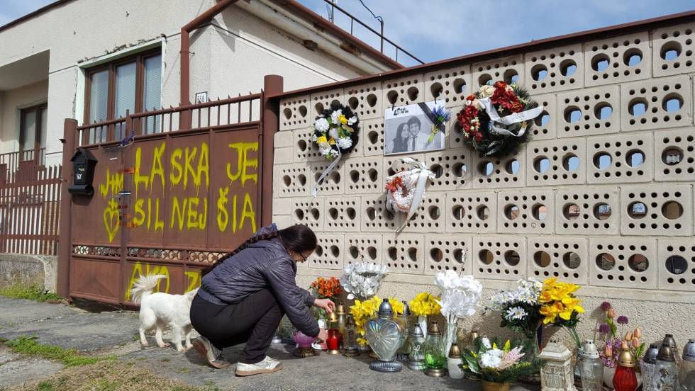 A senhora Regina coloca as velas e as flores que os cidadãos deixaram às portas da casa do Kuciak e Kusnirova, em Velka Maca, na quinta-feira
