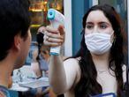 FILE PHOTO: A waitress takes the temperature of customers as they arrive to eat at Dudley's as restaurants are permitted to offer al fresco dining as part of phase 2 reopening during the coronavirus disease (COVID-19) outbreak in the Lower East Side neighborhood of Manhattan in New York City, U.S., June 27, 2020. REUTERS/Andrew Kelly/File Photo
