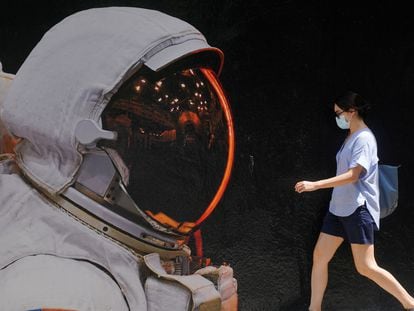 Mulher com máscara de proteção passa por muro pintado em Hong Kong, onde ocorreu caso de reinfecção por covid-19.