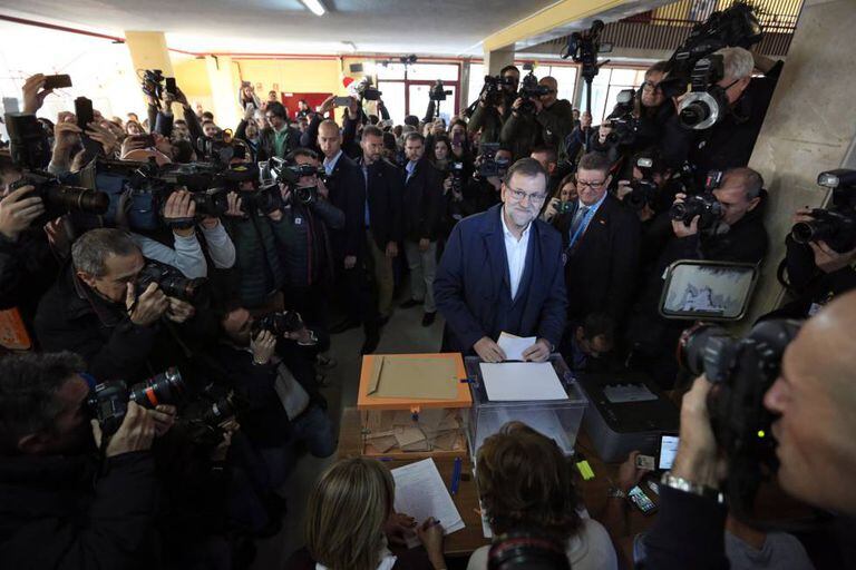 O premiê Mariano Rajoy vota neste domingo, cercado por jornalistas.